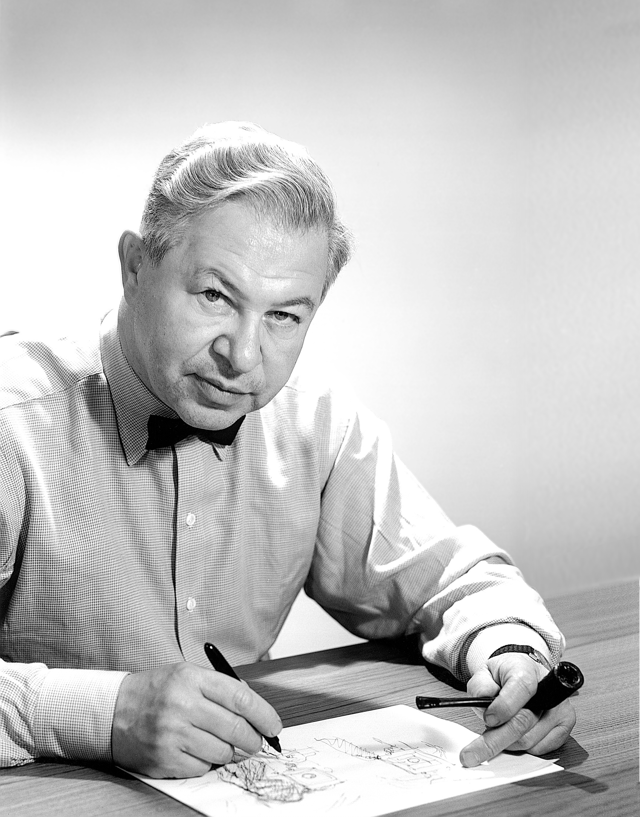 Arne Jacobsen sitzt am Schreibtisch. Designer hinter Holmegaards Royal-Serie