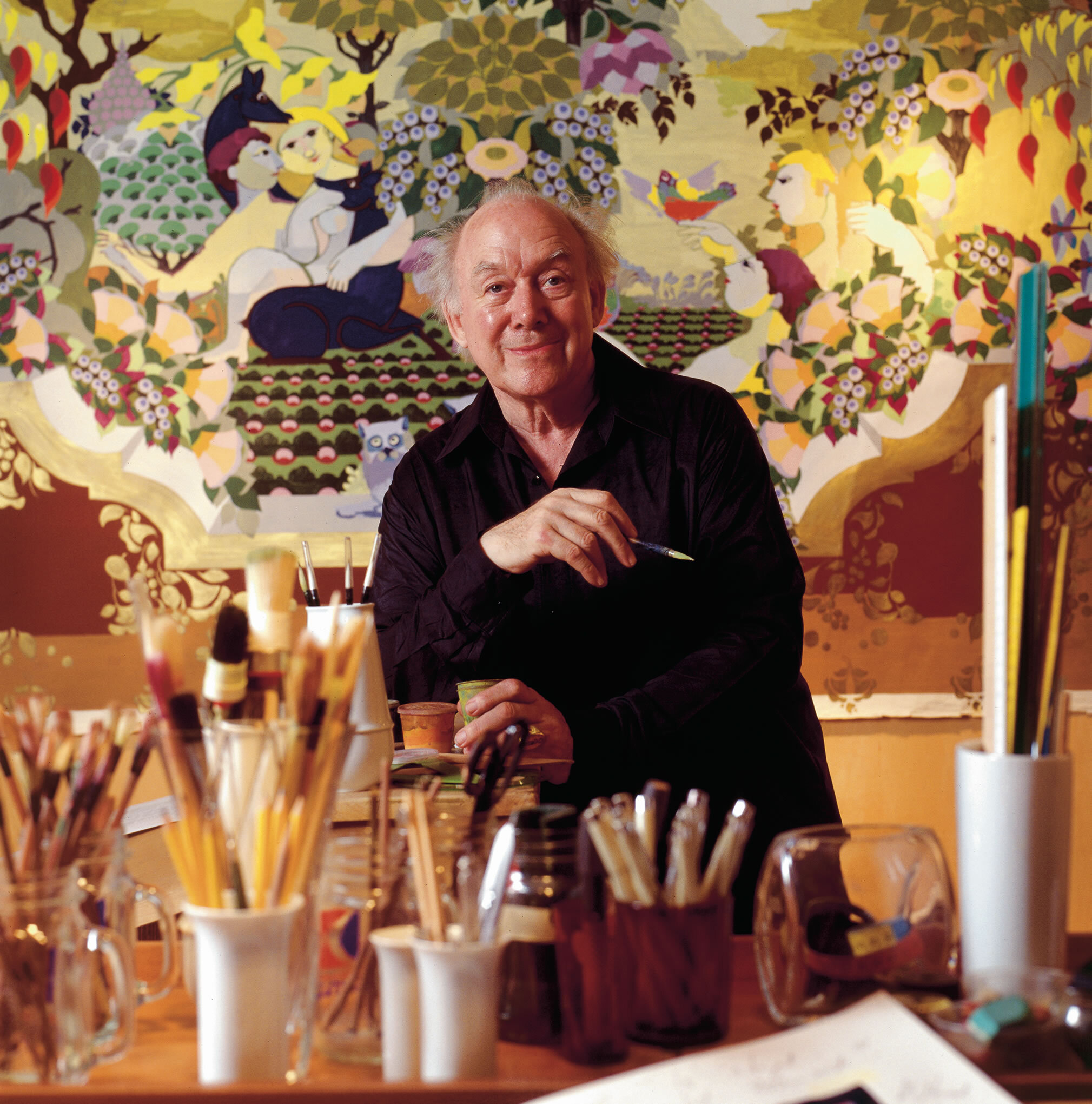 Bjørn Wiinblad mit Pinsel vor Malerei mit einer Fülle von Farben