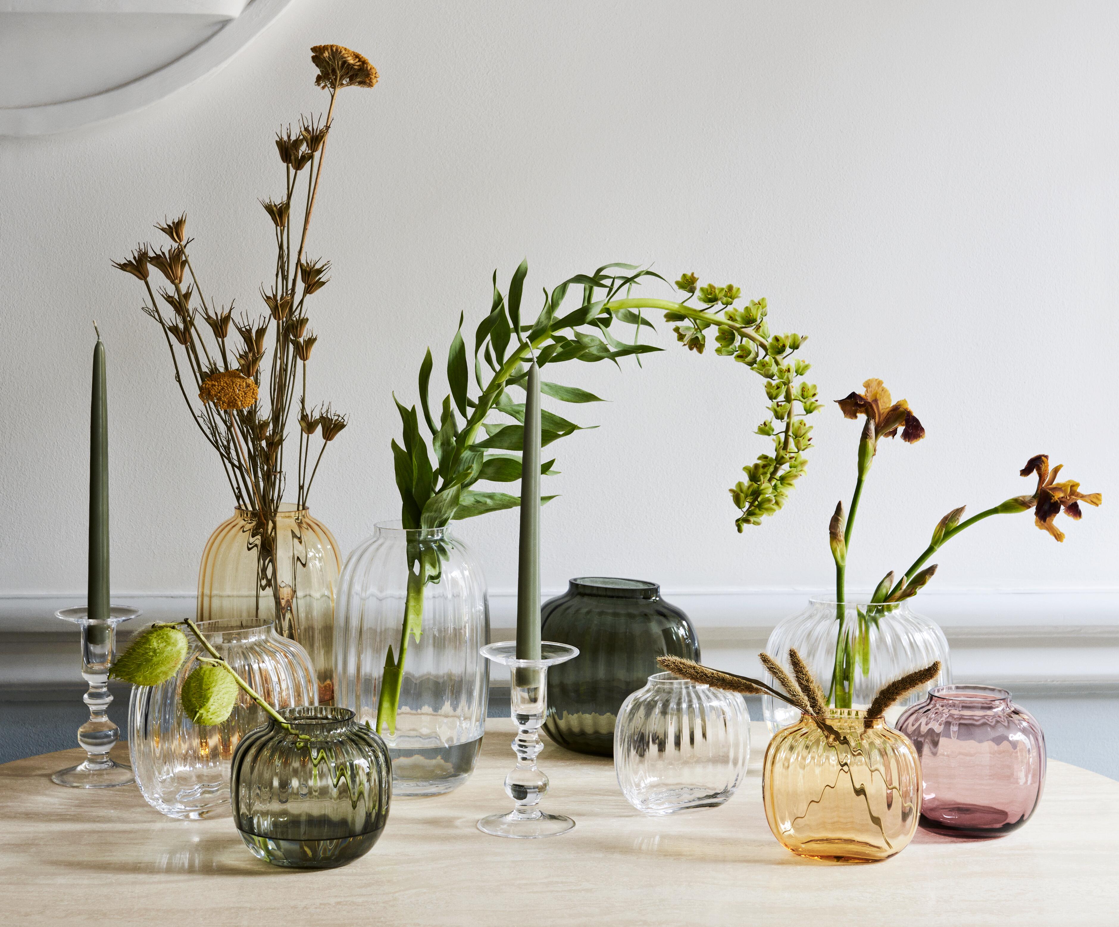 Primula vases gathered on a table with flowers in them, Holmegaard