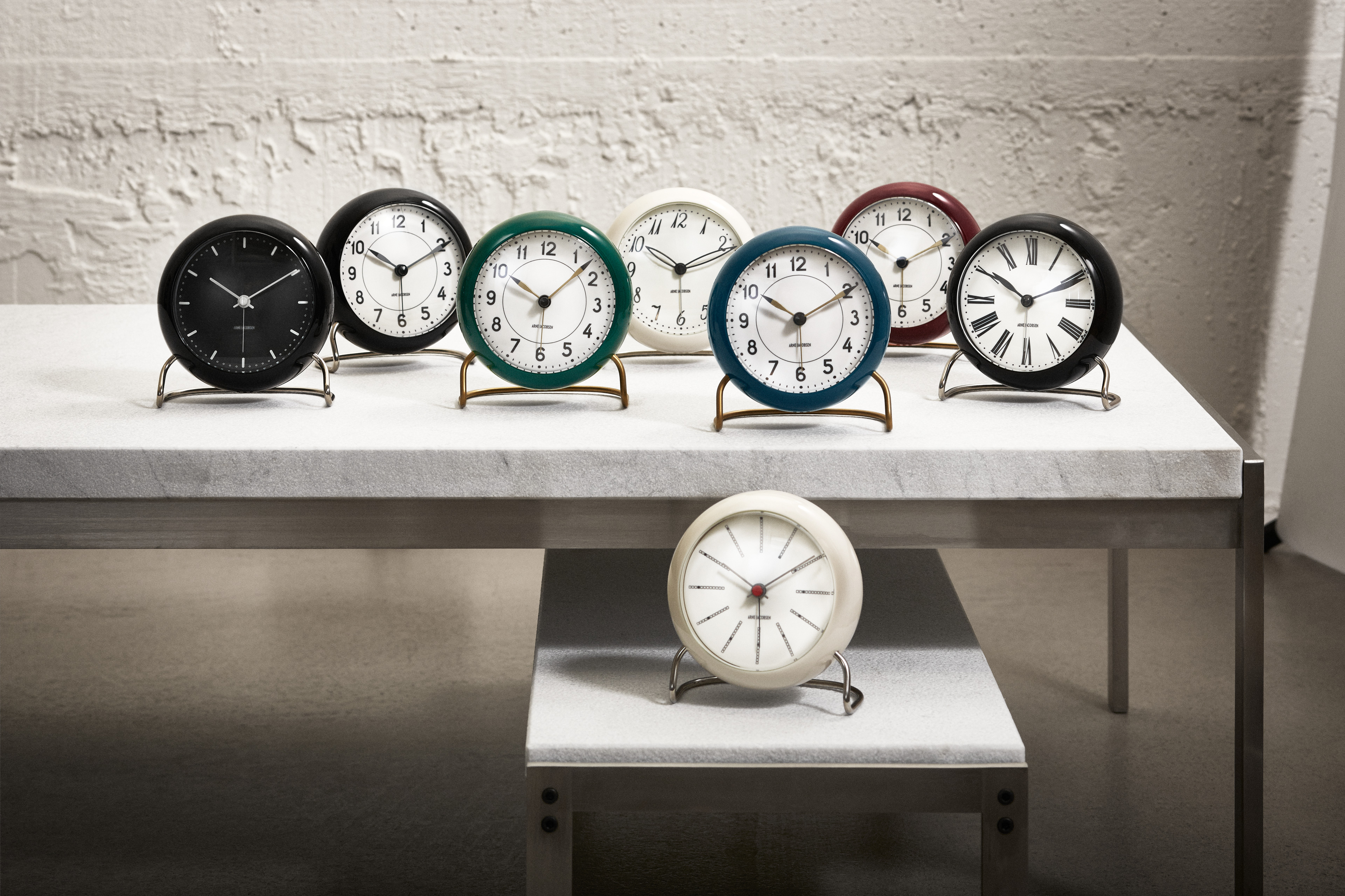 Bordklokker av Arne Jacobsen Clocks i forskjellige farger på bordet