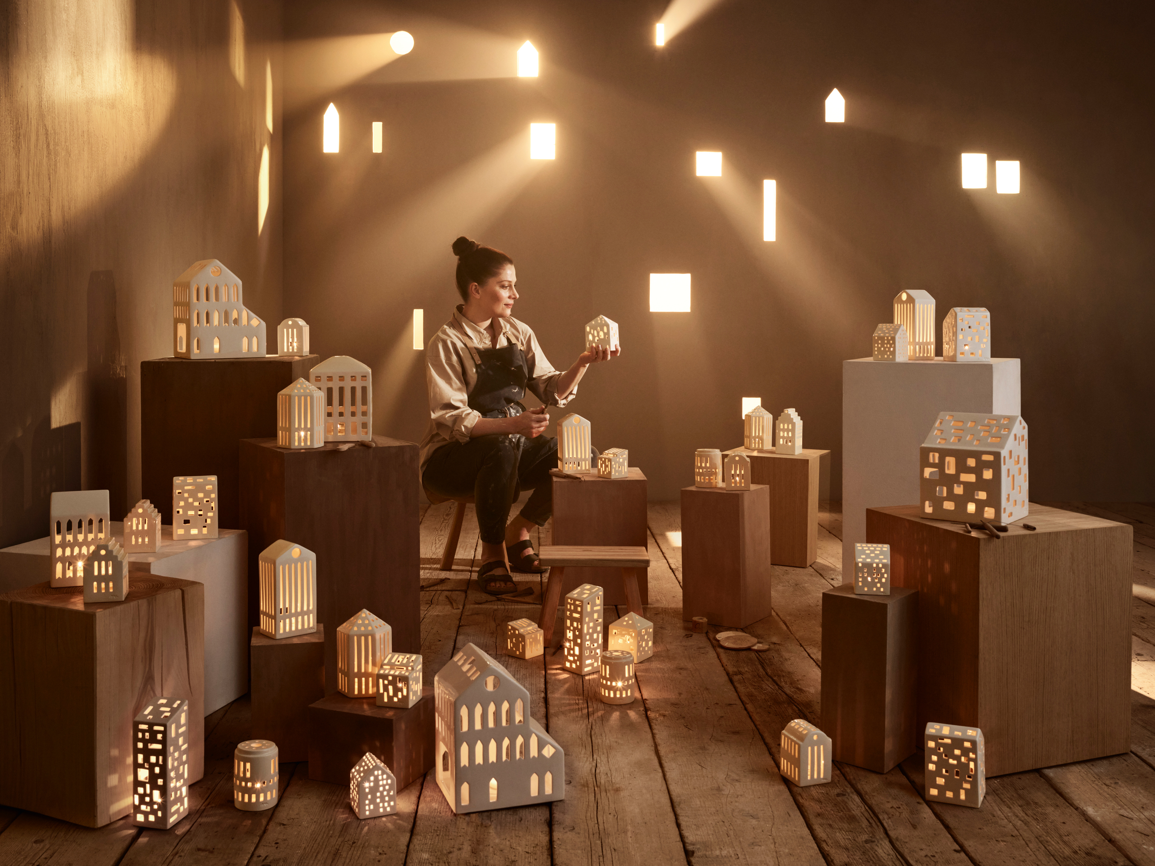 Frau sitzt auf dem Hocker zwischen Urbania Leuchttürmen von Kähler in vielen verschiedenen Größen