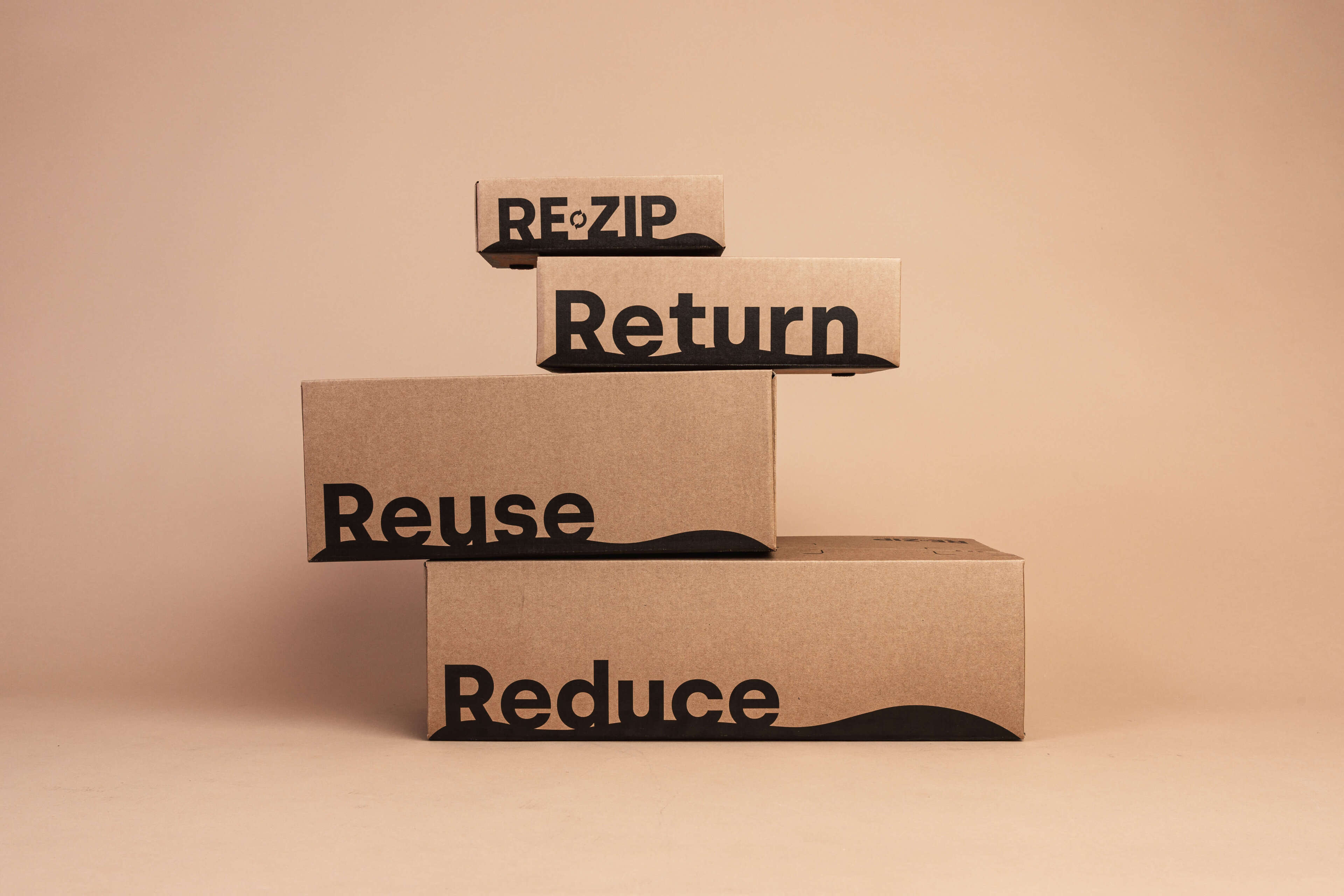 Æsker fra RE-ZIP stablet ovenpå hinanden med teksten "RE-ZIP, Return, Reuse, Reduce"