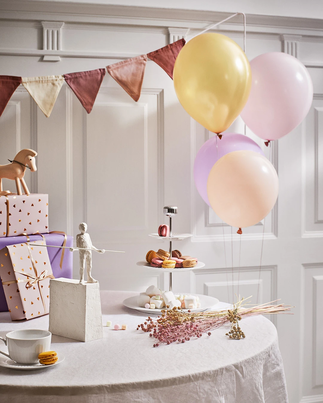 Födelsedagsdukning med kakfat, pastellfärgade ballonger och presenter – dekorerad med nordiskt porslin och Kähler-figurer