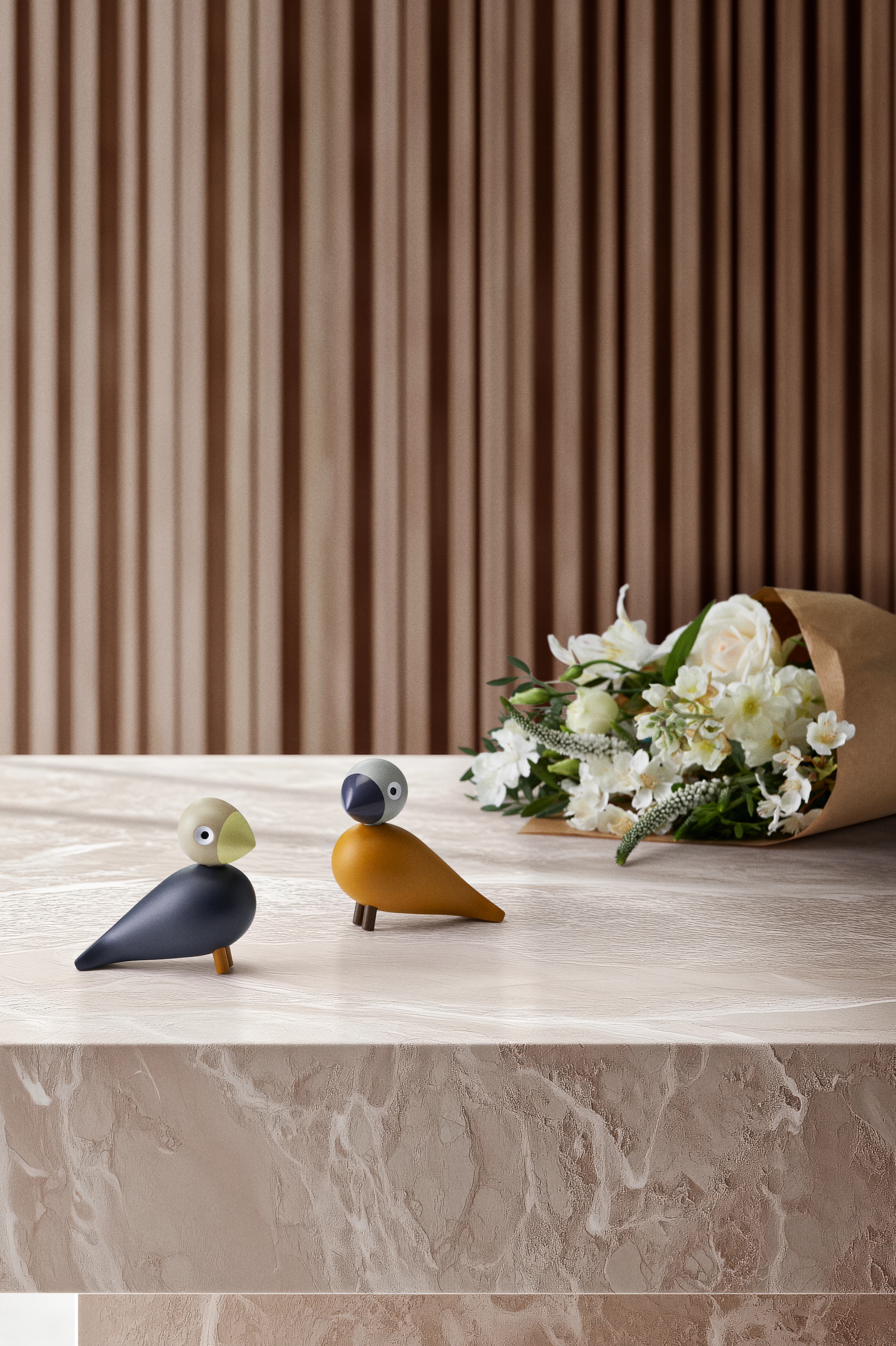 Kay Bojesen Babies wooden birds on marble table with flower bouquet and wood panel background
