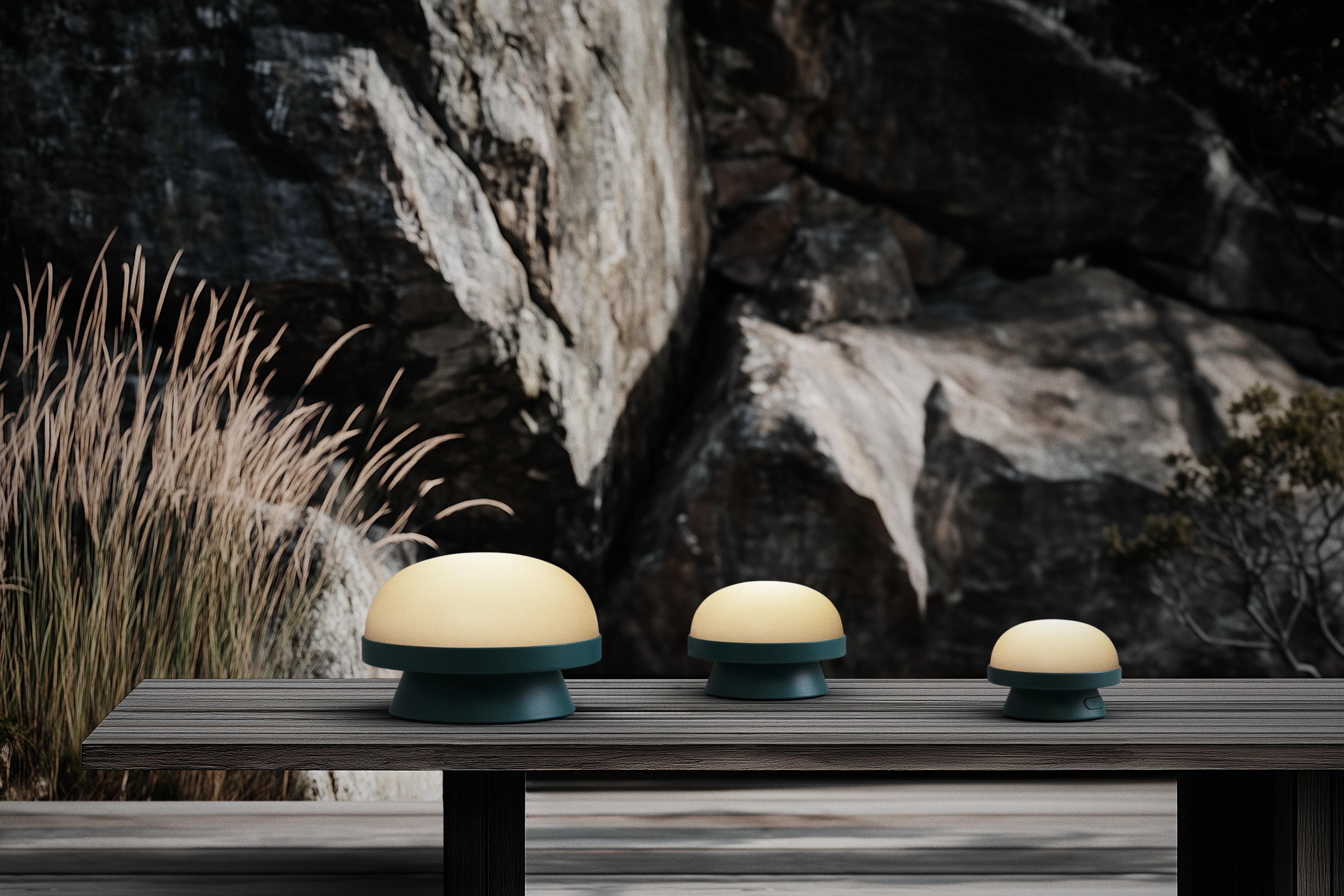 Tre svampeformede lamper på et træbord med sten og græs i baggrunden