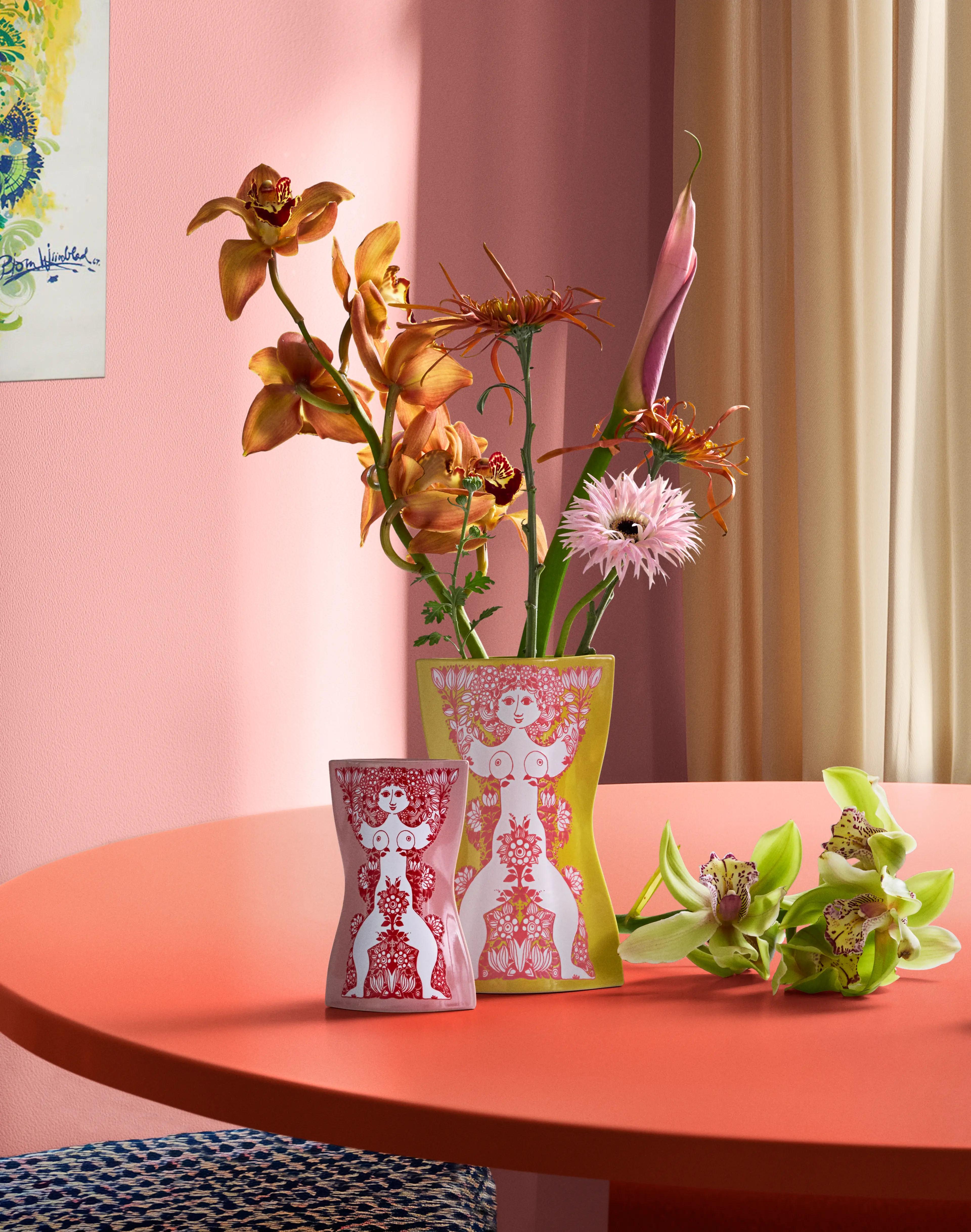 Bjørn Wiinblad Nina vas och minivas med blommor på ett runt bord i färgstark miljö.