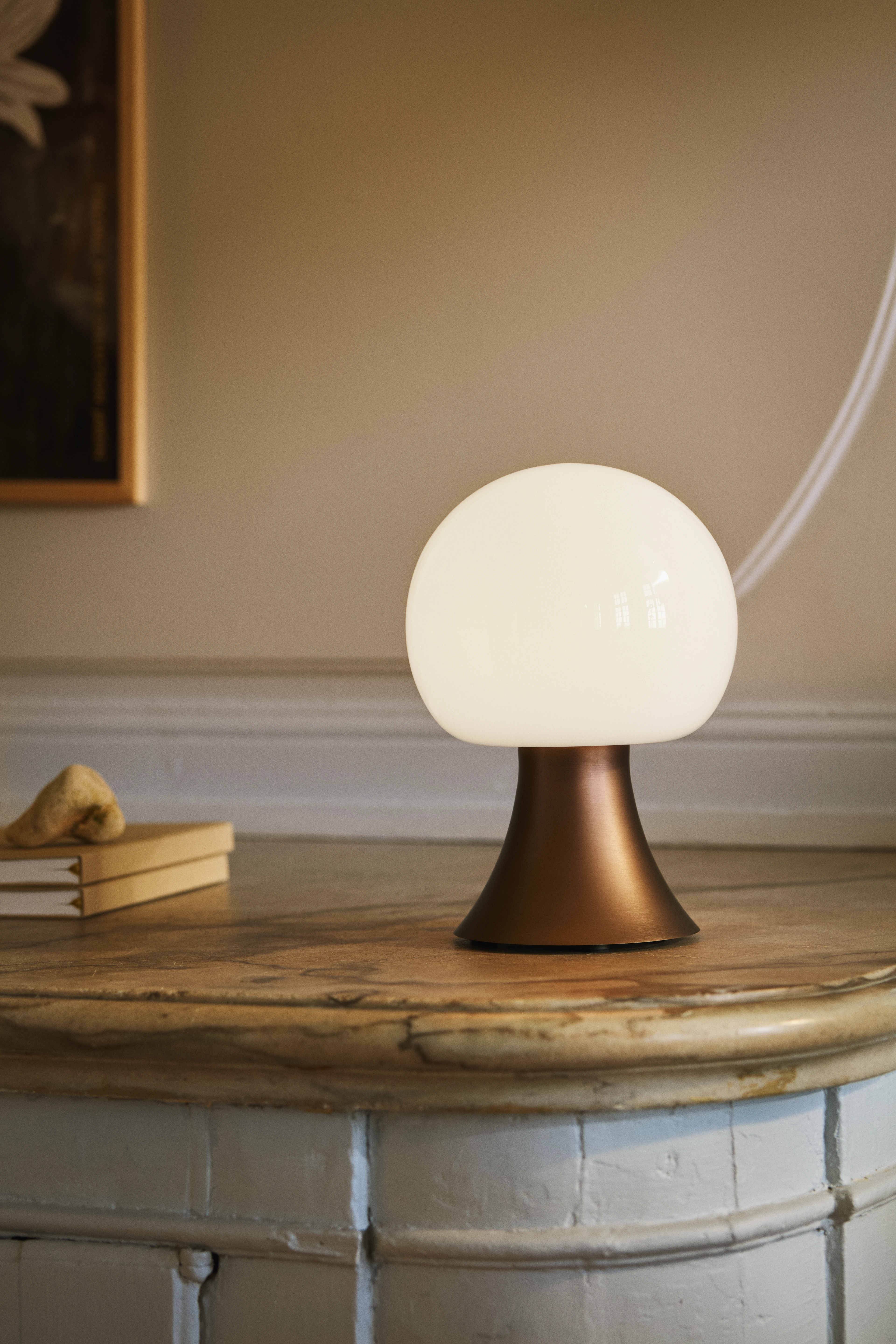 Holmegaard Noor table lamp with opal white shade and copper-toned base on marble tabletop