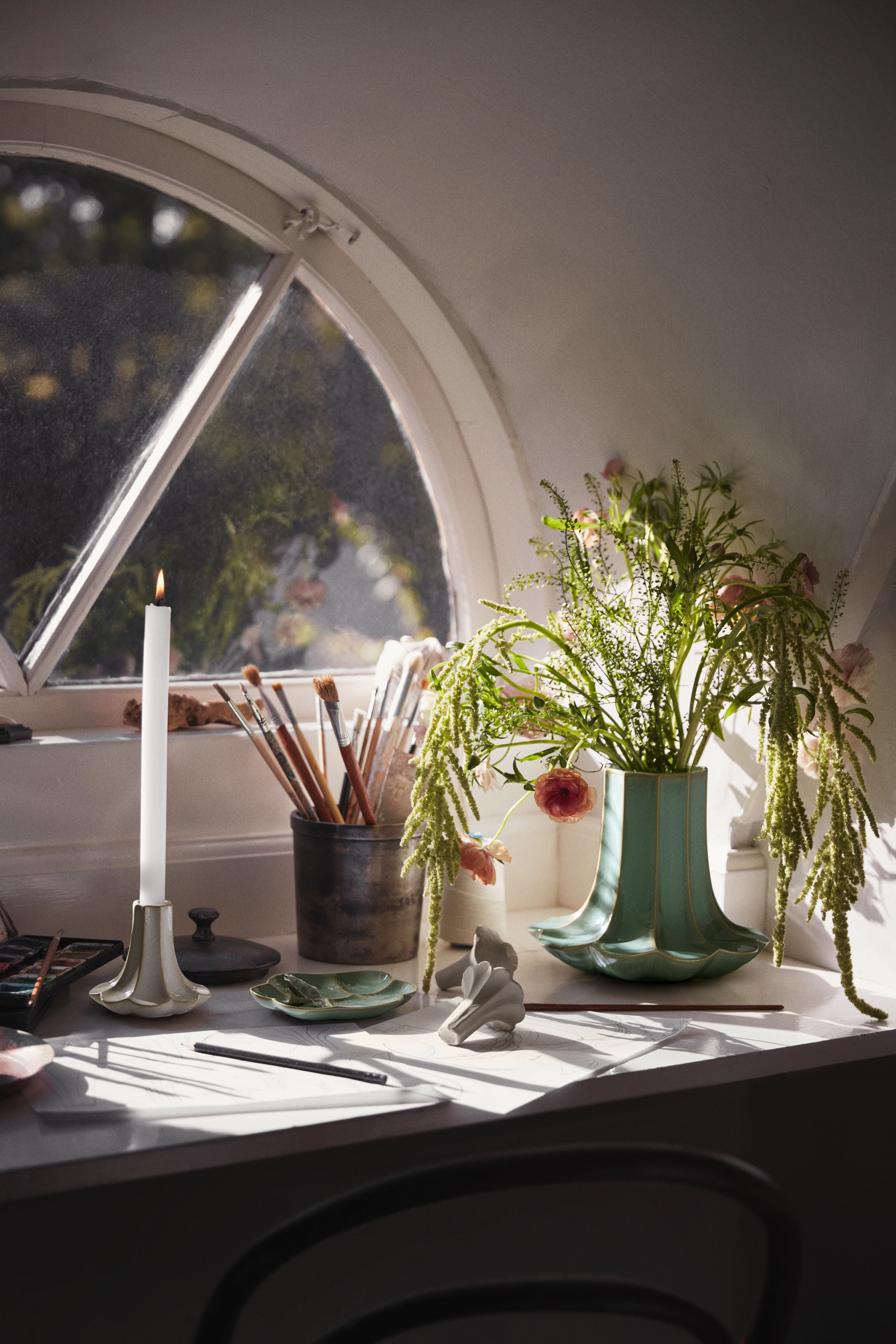 Kähler Kantarel vase og lysestage med blomster placeret ved et vindue i et lyst, kreativt interiør.