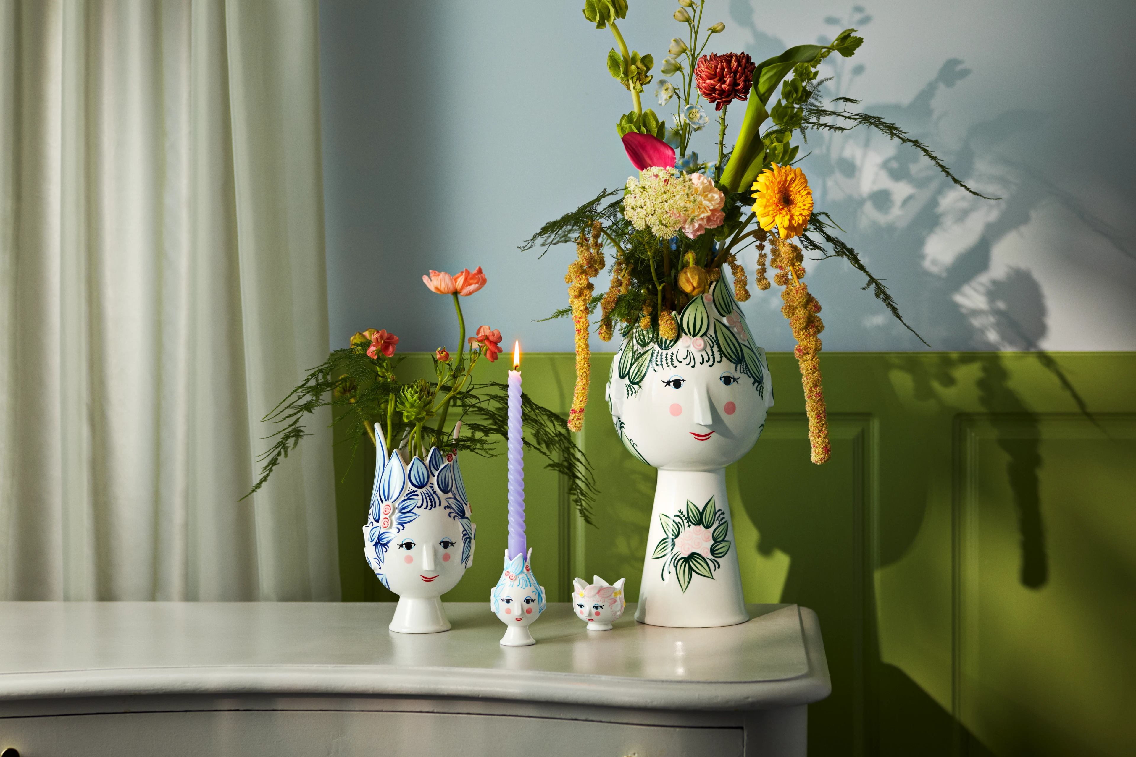 Bjørn Wiinblad Titania vaser med fargerike blomster arrangert på et bord i et lyst interiør.