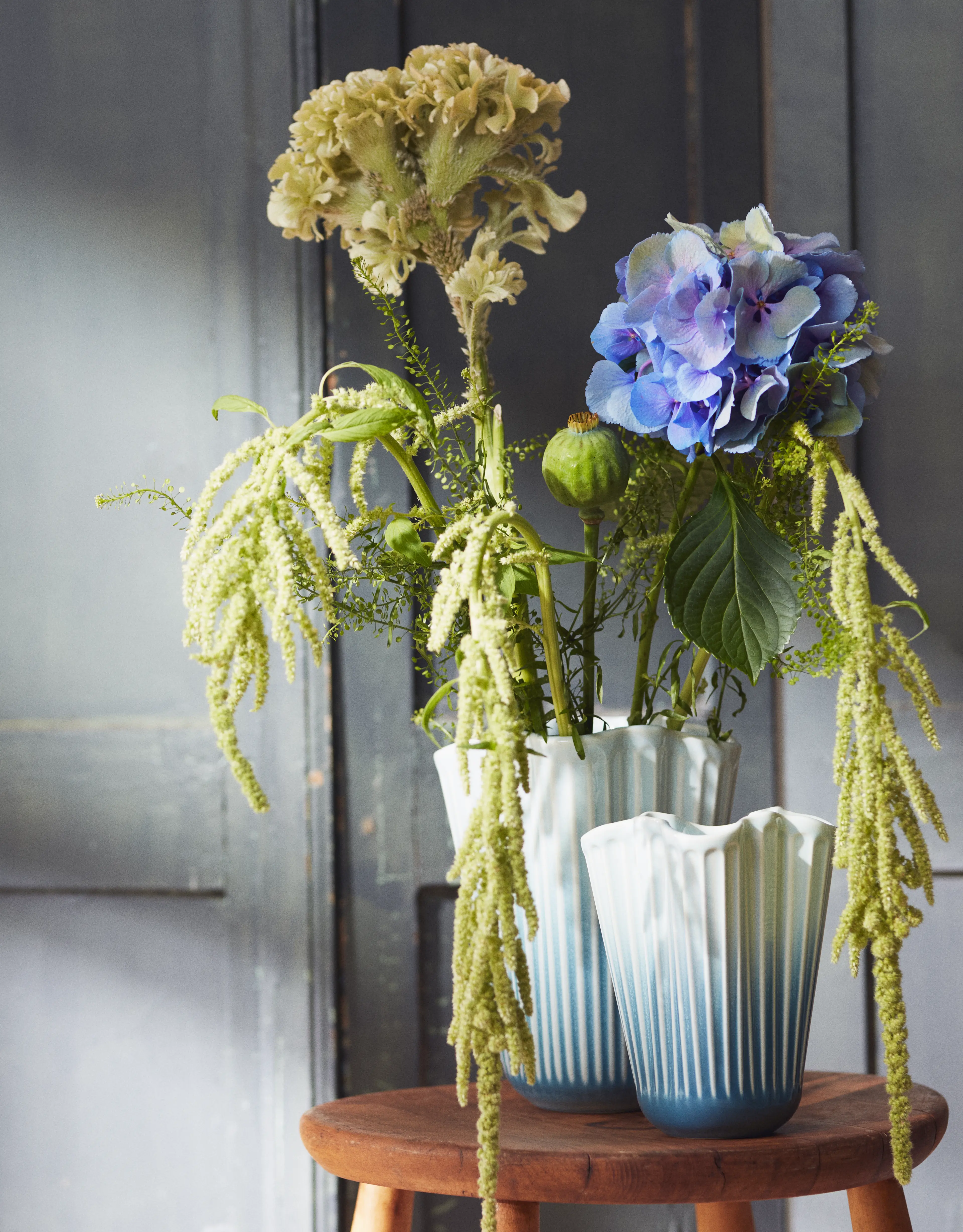 Kähler Hammershøi Unfold Vase mit Blumen auf einem Hocker in stimmungsvollem Ambiente.