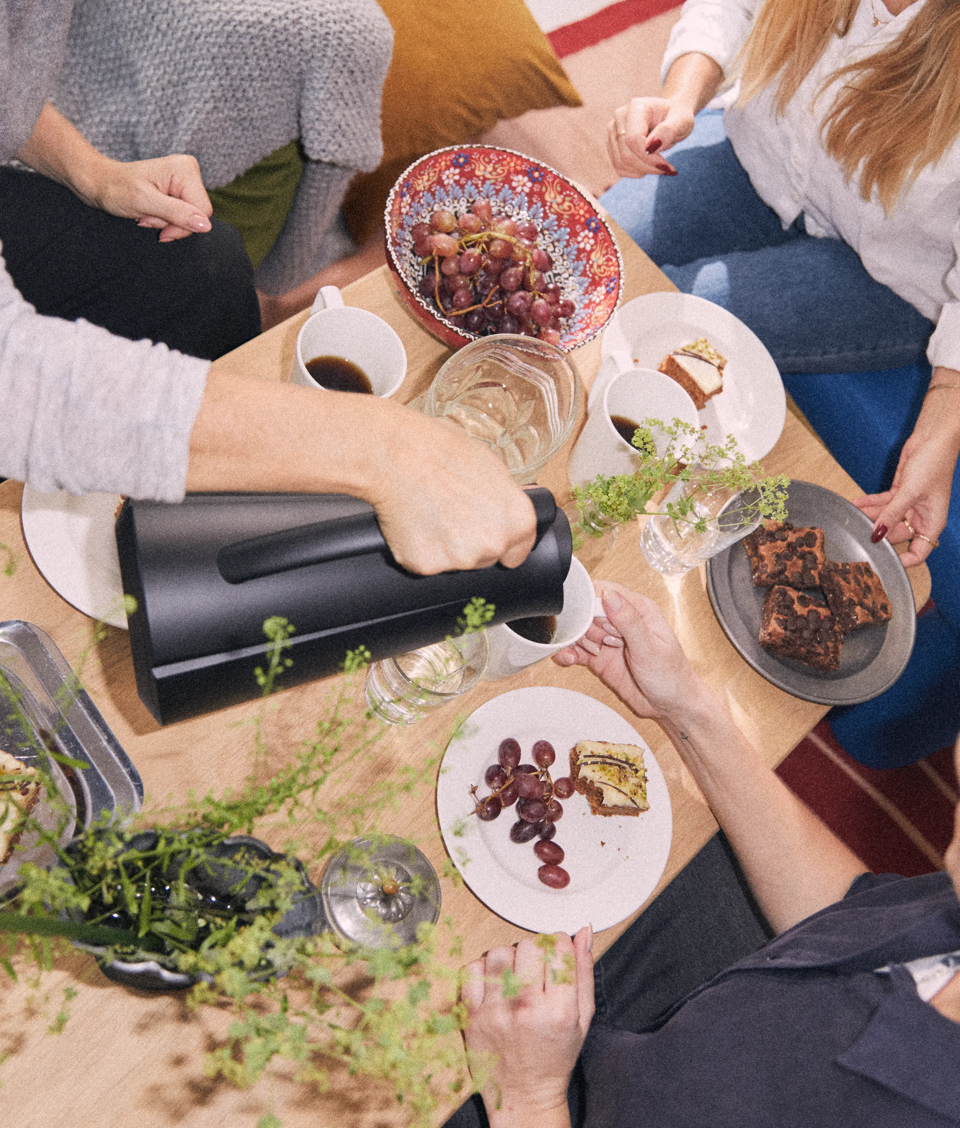 Rosendahl Grand Cru servering med kaffe, kake og snacks delt rundt et bord i hyggelig lag.