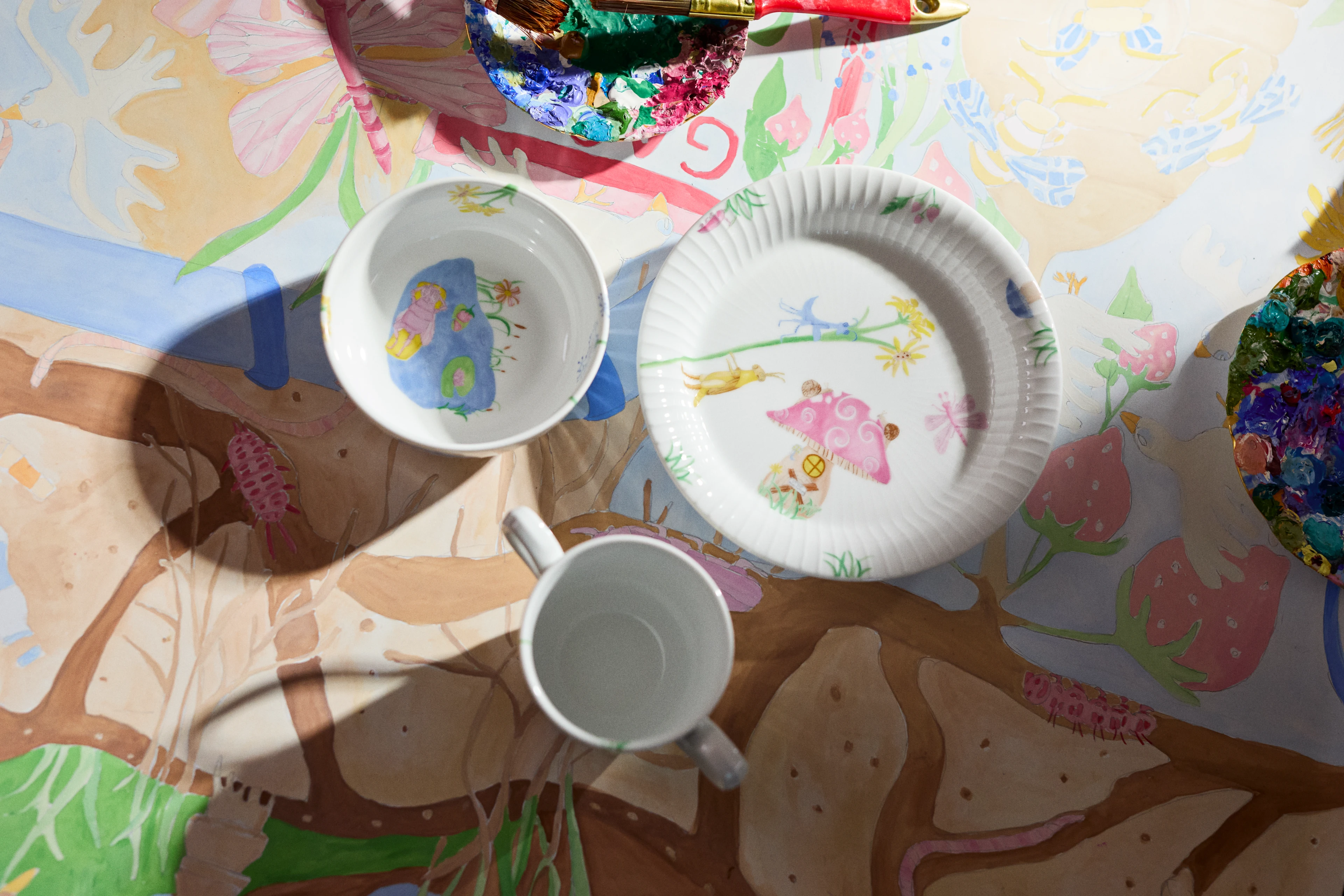 Kähler Hammershøi Kids kopp, skål og tallerken med eventyrmotiv på kreativt malebord.