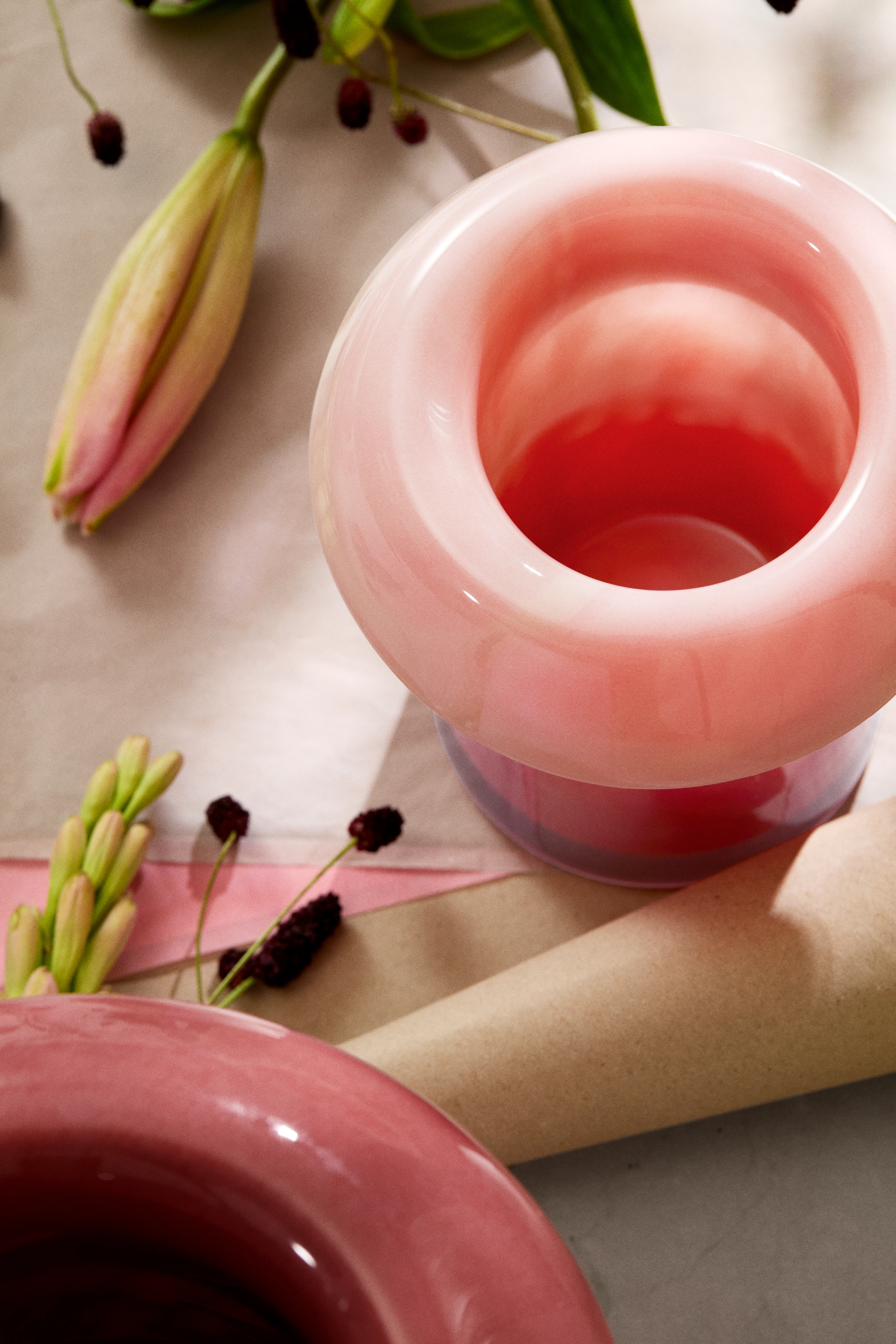 Holmegaard Soma glassvase i rosa, nærbilde av åpning med blomster og dekor på bord