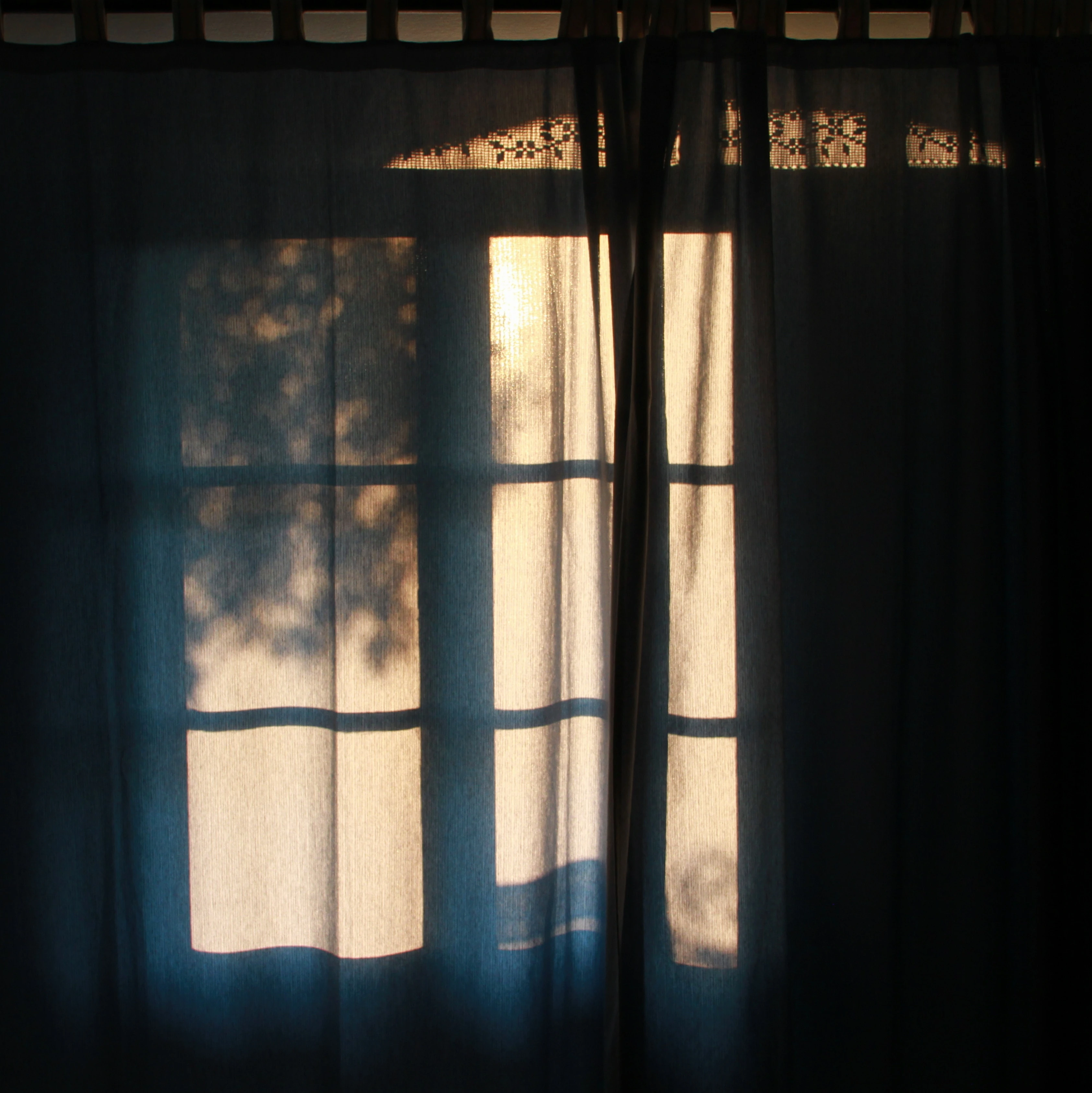 Window with sunlight streaming through, framed by curtains