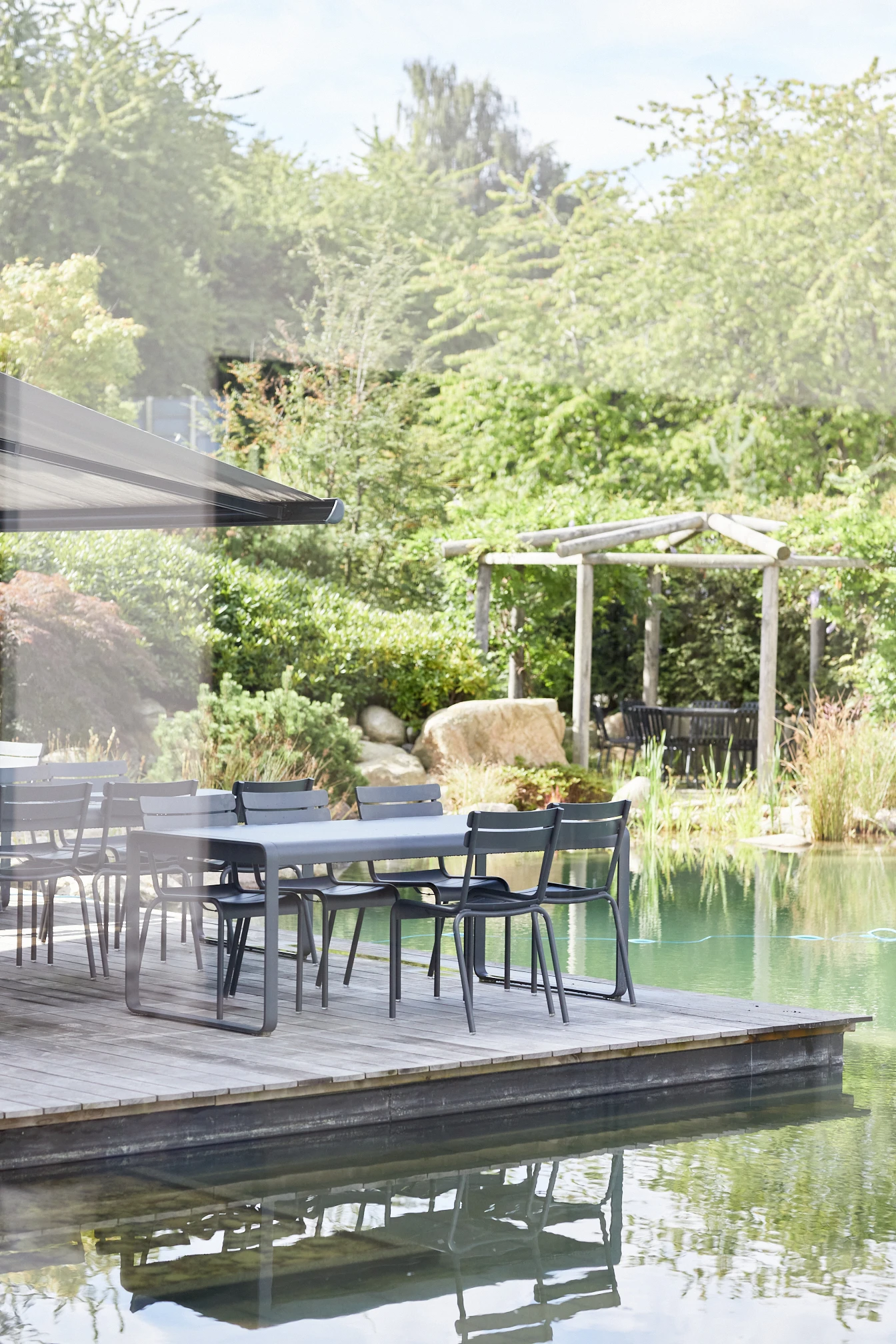Exterior view of Rosendahl Design Group's main building by a lake, showing an outdoor setting with tables and chairs