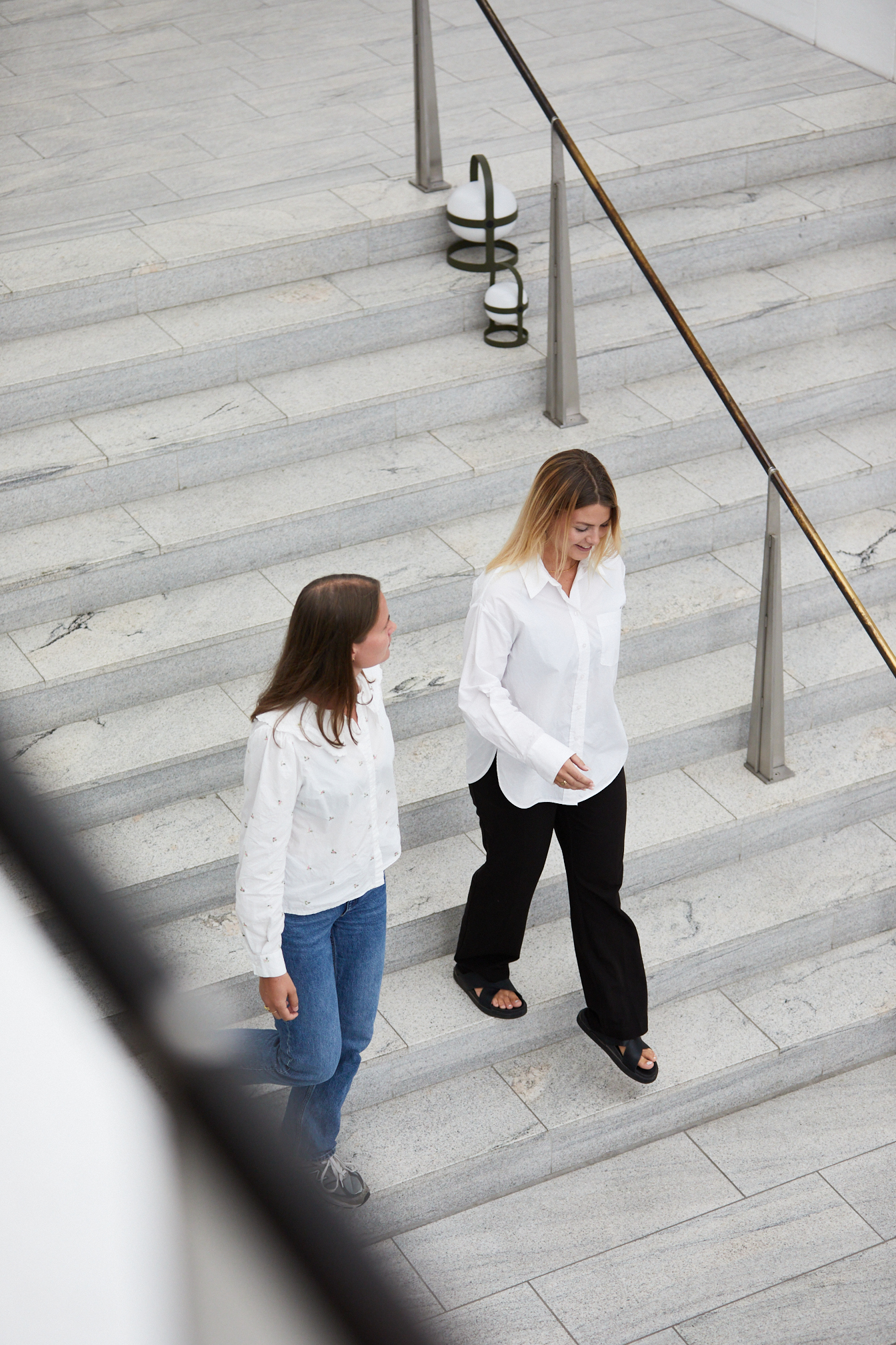 Two young women walking down the stairs in the Rosendahl design group building. 