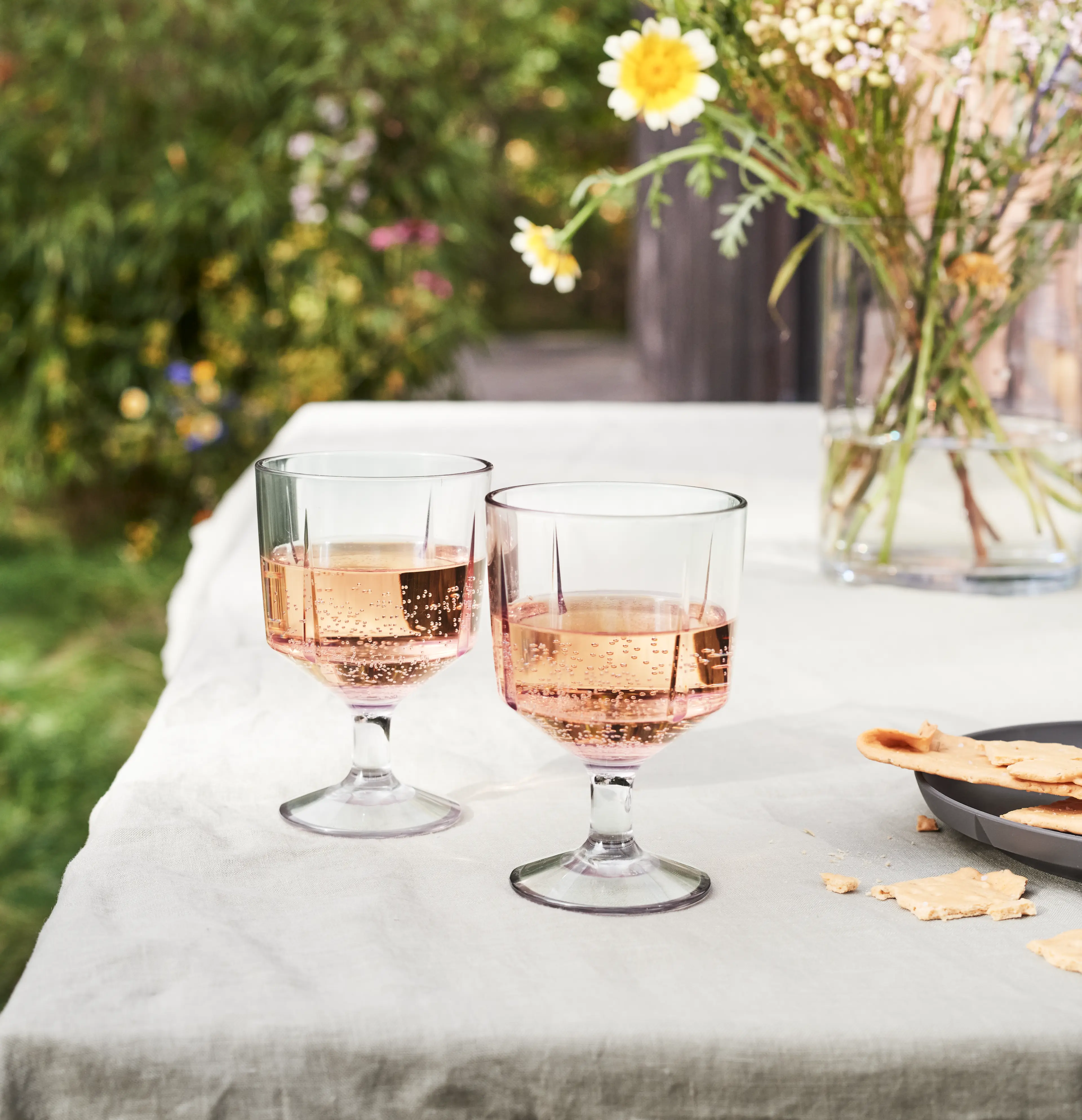 To glas på bord med blomster i haven – elegant gave til sommerhygge