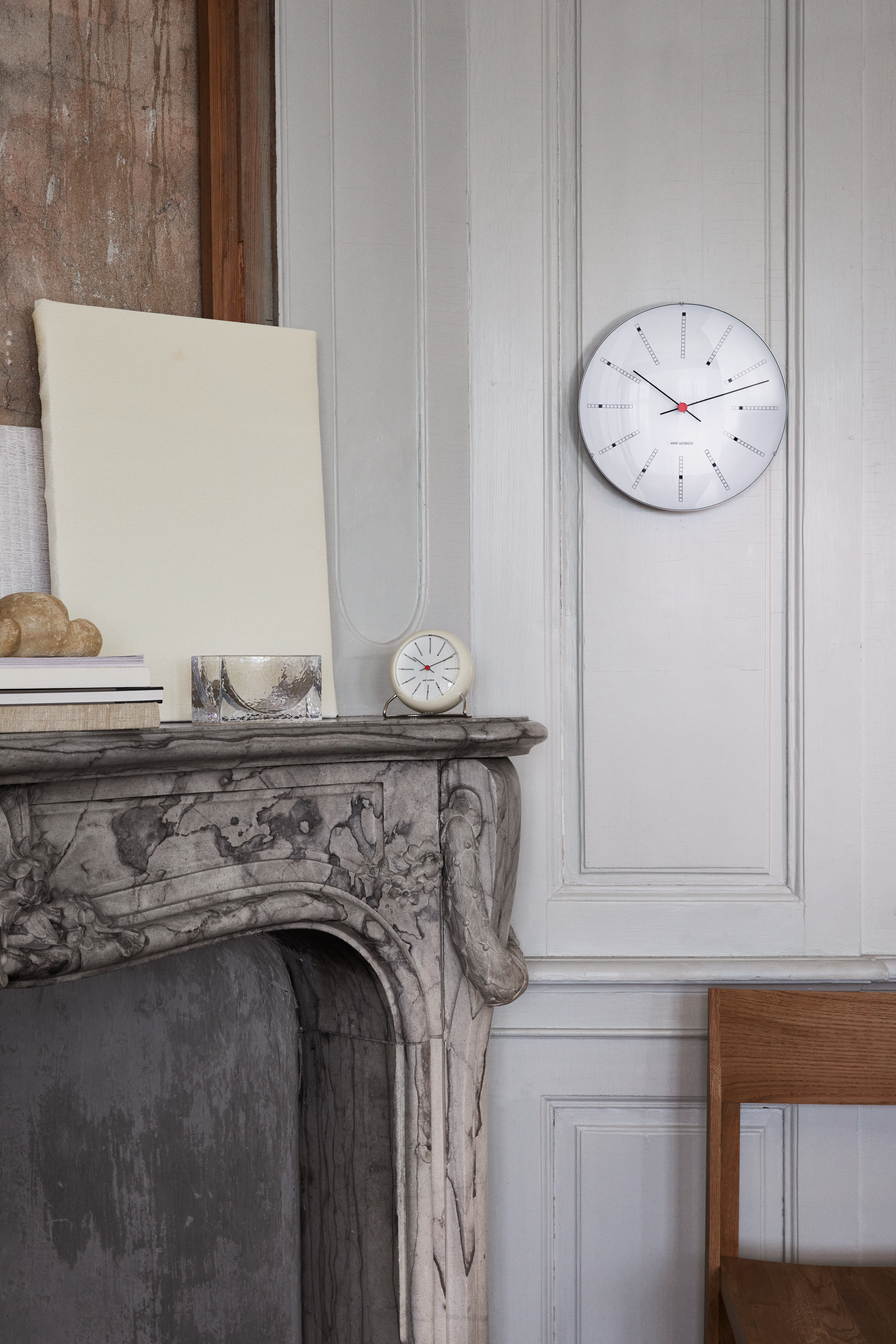 Arne Jacobsen Clocks Bankers wall clock and table clock styled in a classic interior with fireplace.
