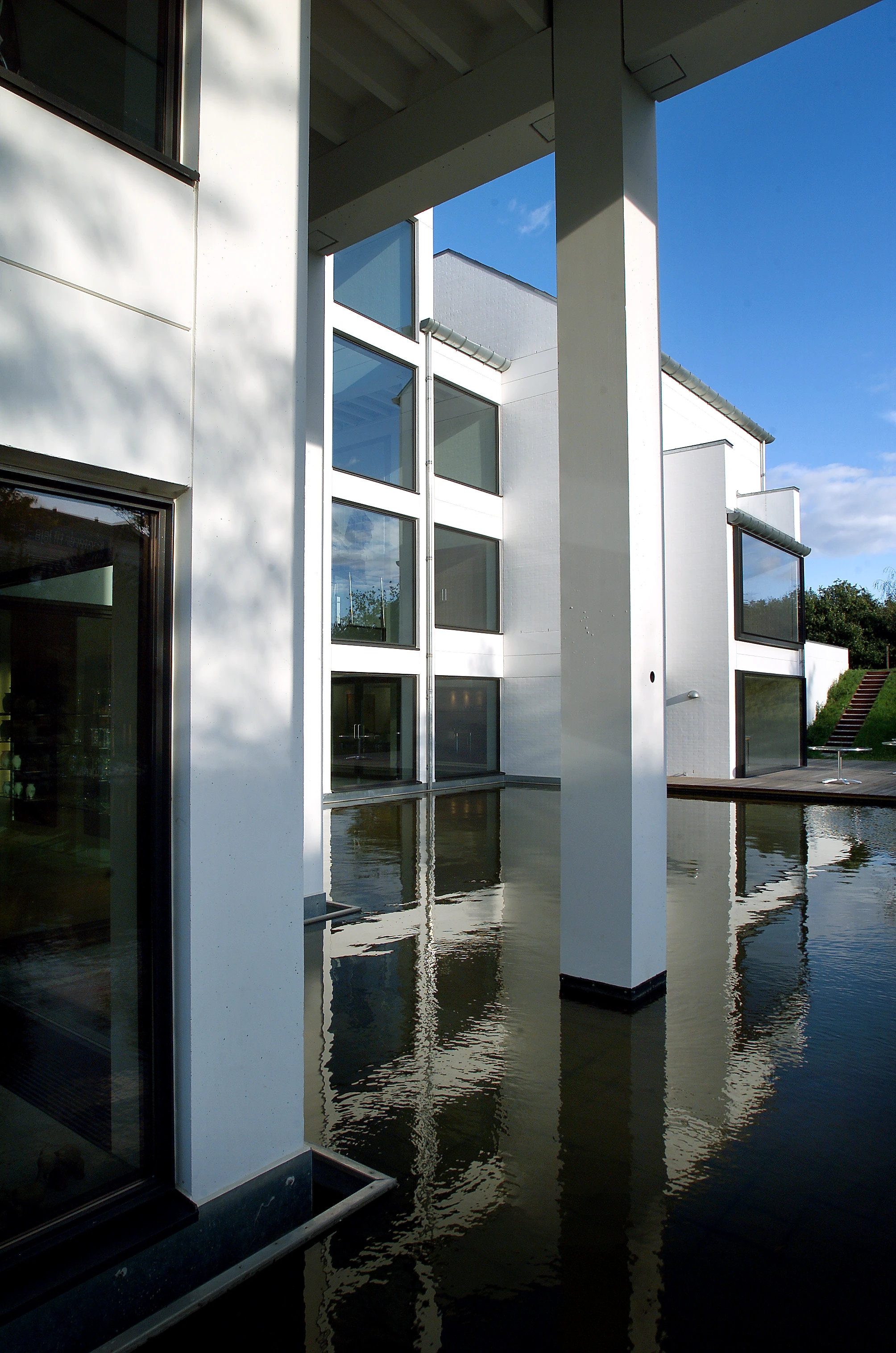 Rosendahl Design Group headquarters seen from across the lake, with a white building reflecting in the water beneath a clear blue sky