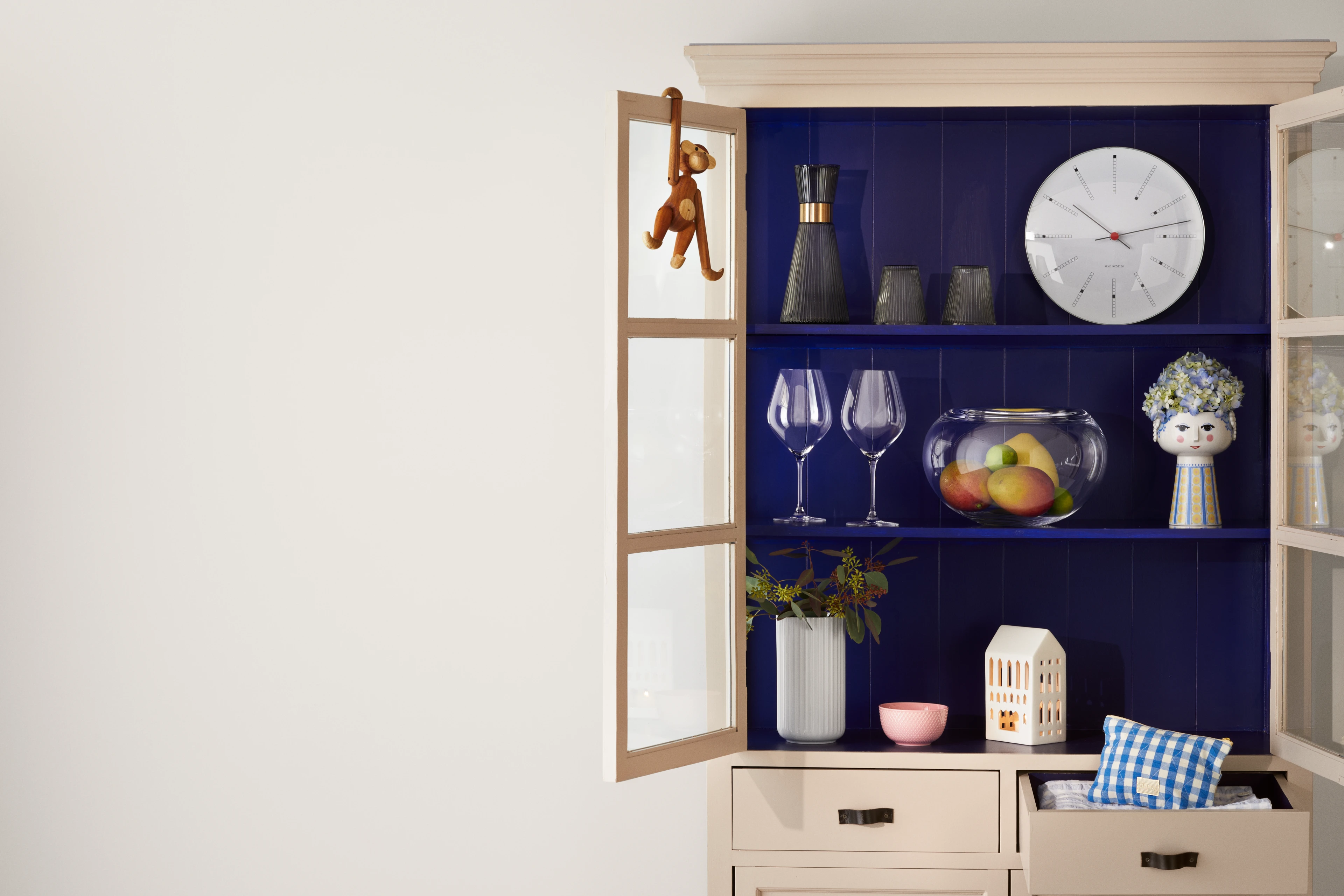 Åbent skab med blå baggrund, Kay Bojesen abe, glas, frugt og dekorative objekter