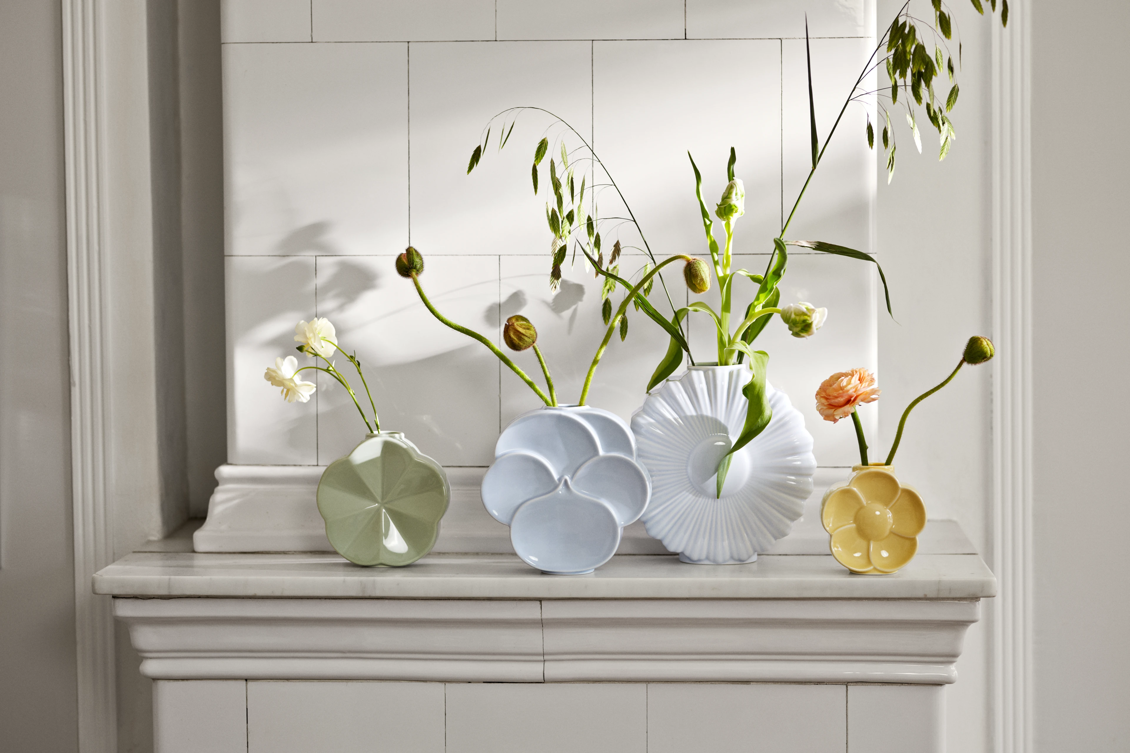 Lyngby Porcelæn Flower vaser med enkle blomster arrangert på en klassisk hylle i et lyst interiør.